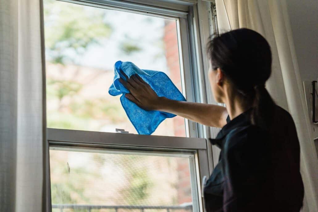 woman cleaning window in house with blue cloth
