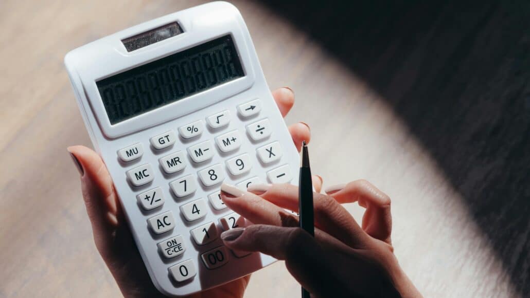 someone tapping buttons on a white calculator