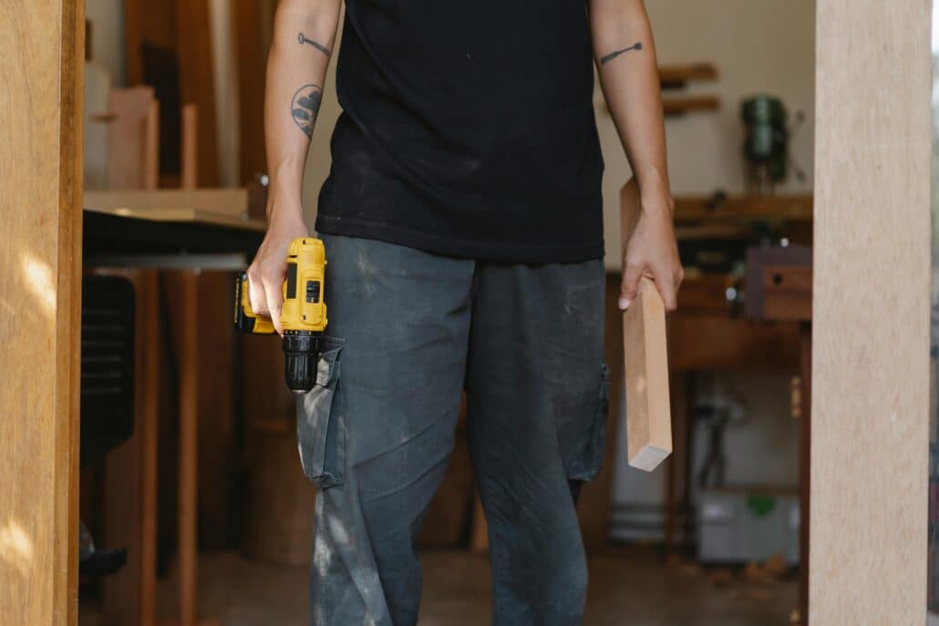 someone holding a hand drill and a wooden plank