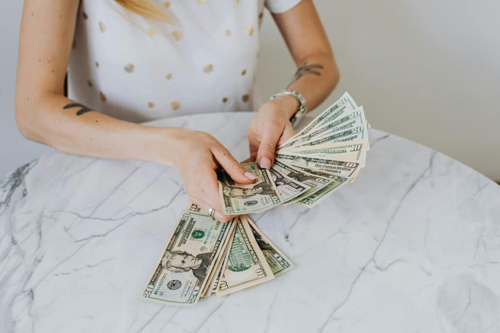 someone counting cash at a white marble table