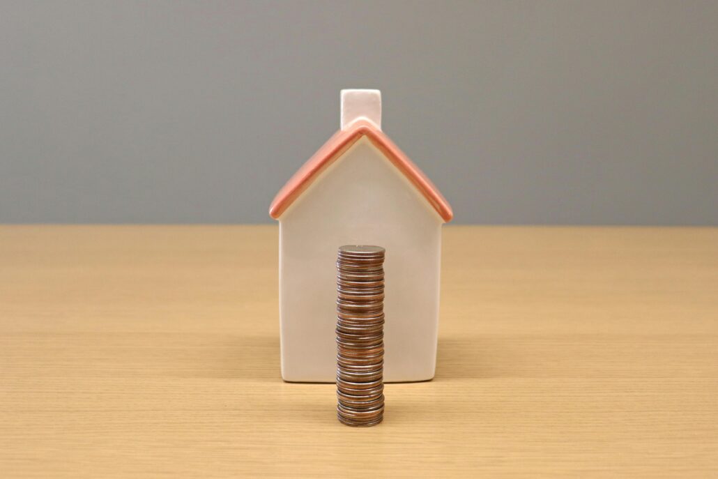 a stack of coins in front of a model house