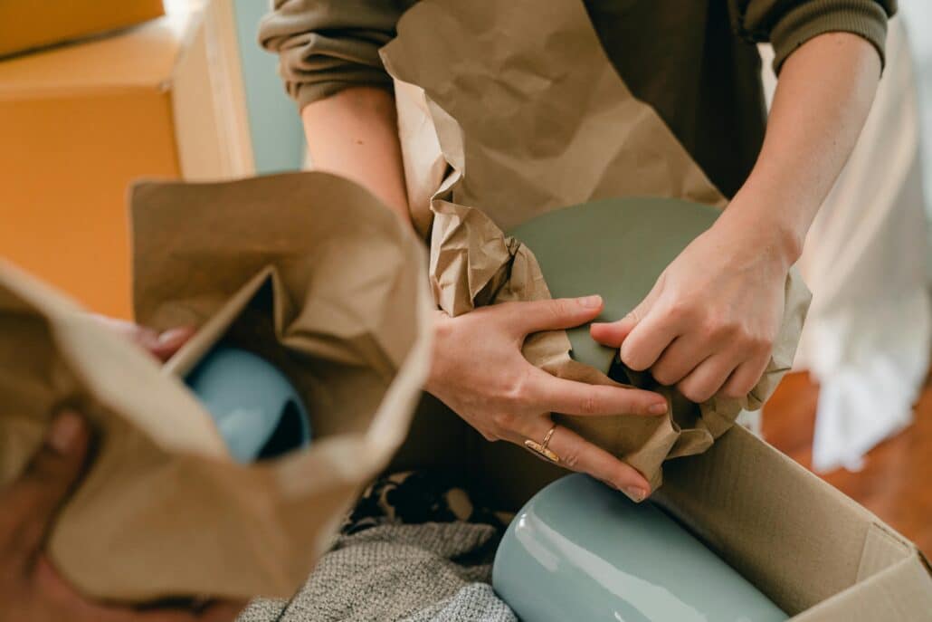 two people wrapping up plates to put them in a moving box