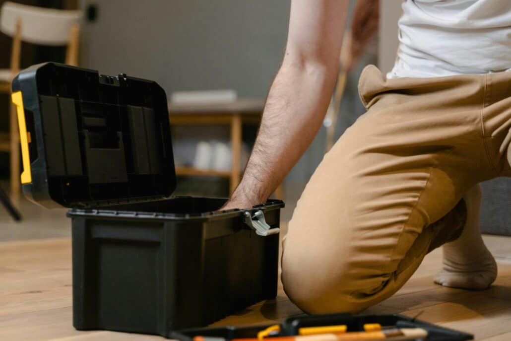 someone kneeling down and reaching into a black toolbox