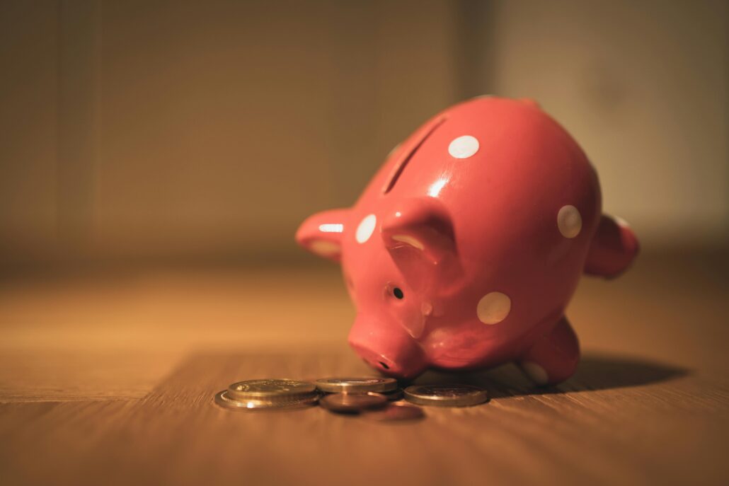 a pink piggy bank with polka dots positioned to look like it's eating coins