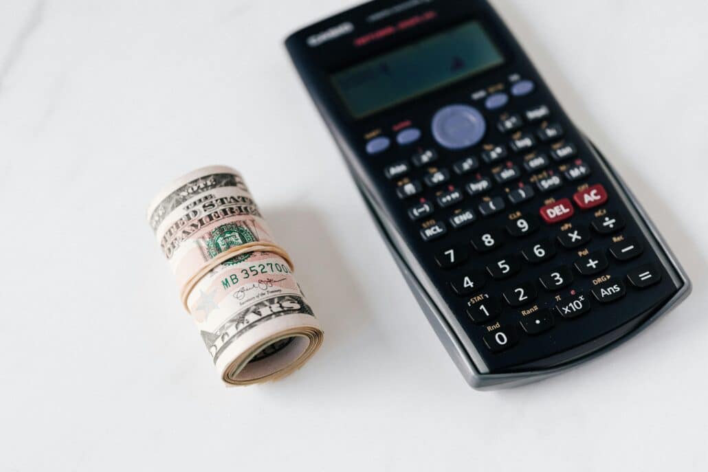 calculator next to a rolled stack of cash